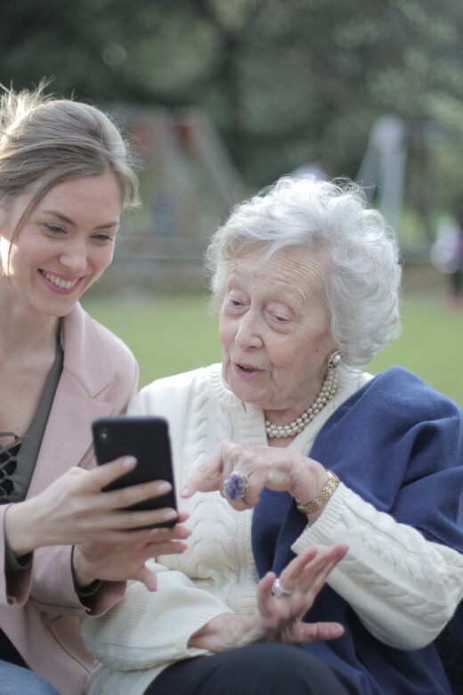 Photo: younger woman and older woman looking at a smartphone in park