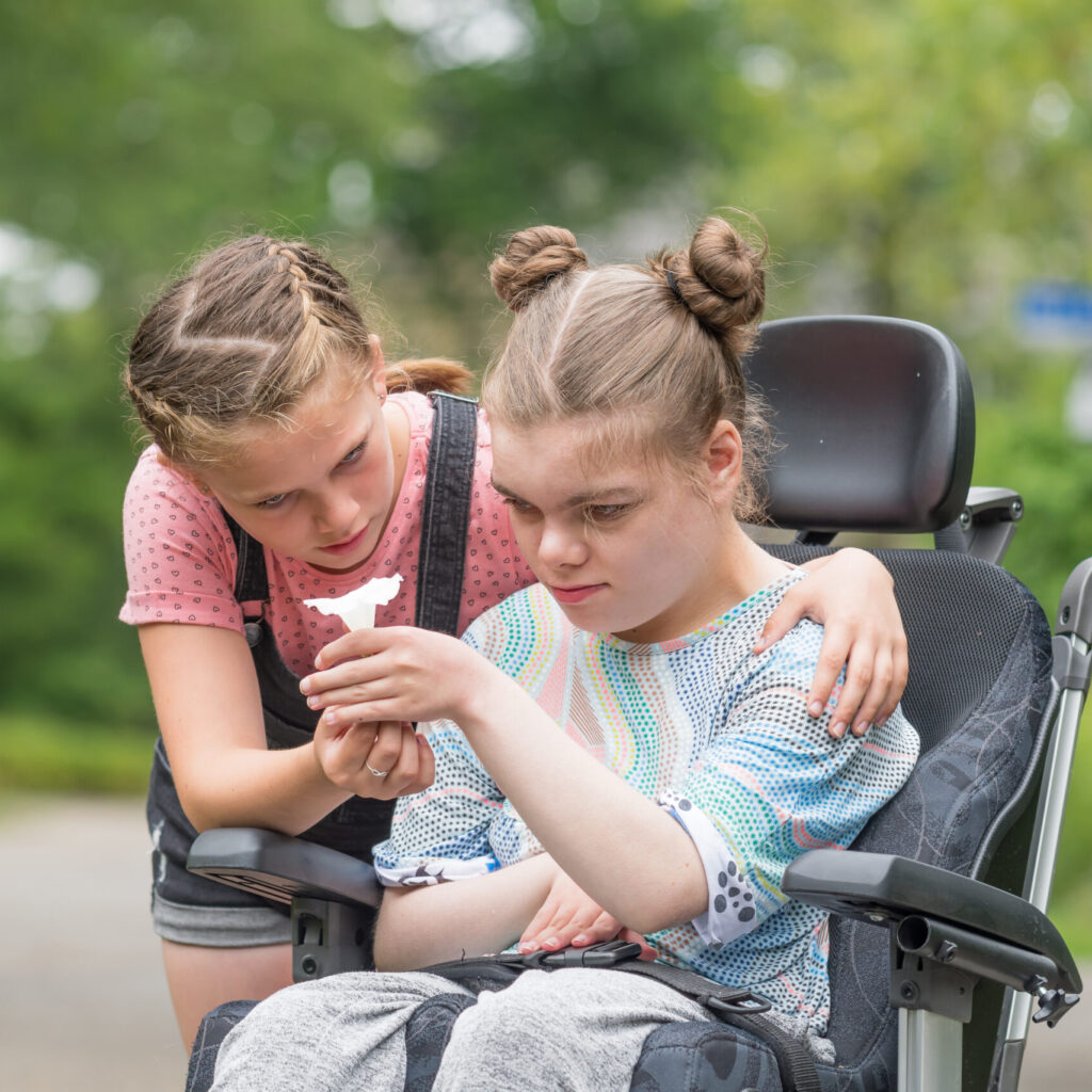 Photo: young girl using wheelchair with peer